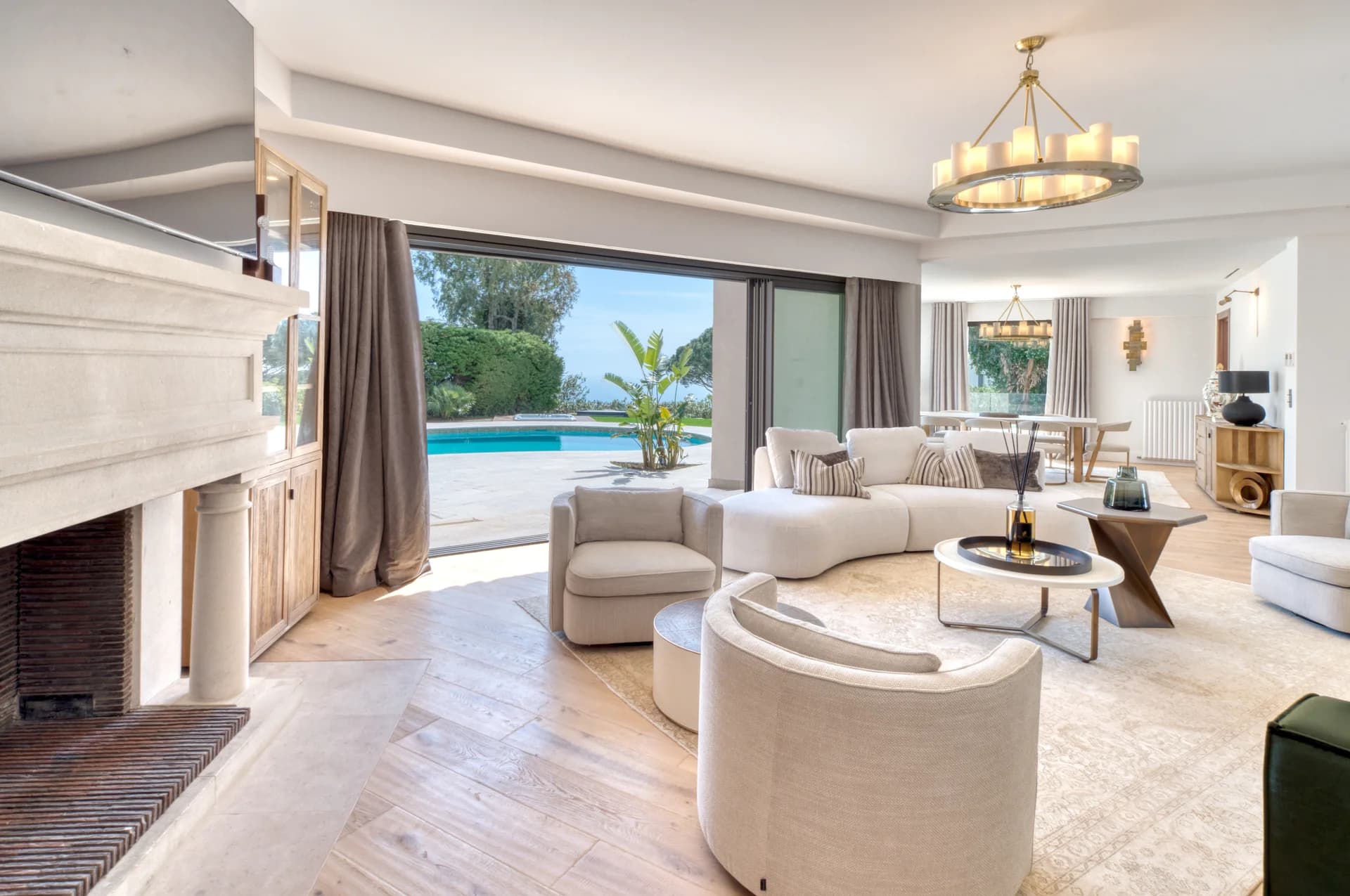 Salon avec cheminée en pierre, baies ouvertes sur la piscine et la mer